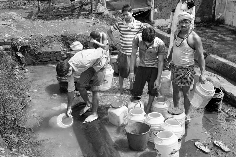 Men and Drinking Water Procurement - Fetching drinking water from a ditch filled by leakage from a pipeline serving a neighboring colony in the outskirts of Dhanbad city, Jharkhand